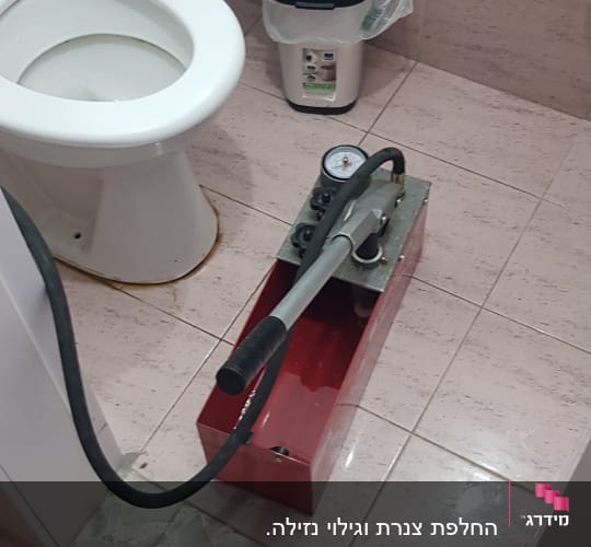 משאבת לחץ אדומה עם מד לחץ בחדר אמבטיה